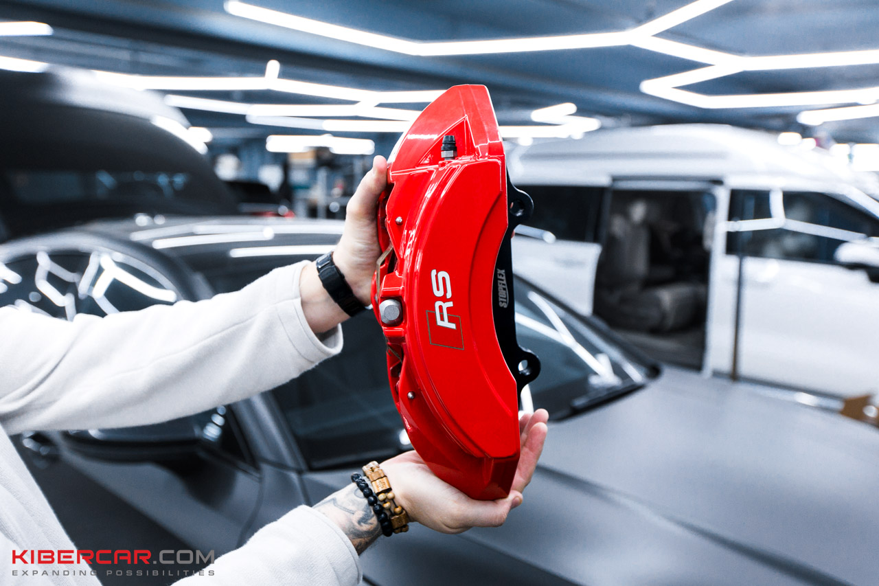 Ярко-красный суппорт Brembo RS с логотипом RS в руках мастера