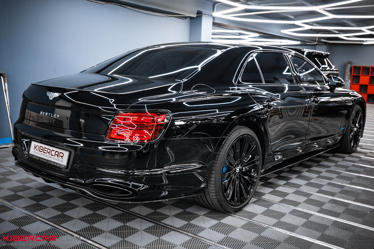Черный Bentley Flying Spur 2025, вид сзади и сбоку: черные диски, голубые суппорты