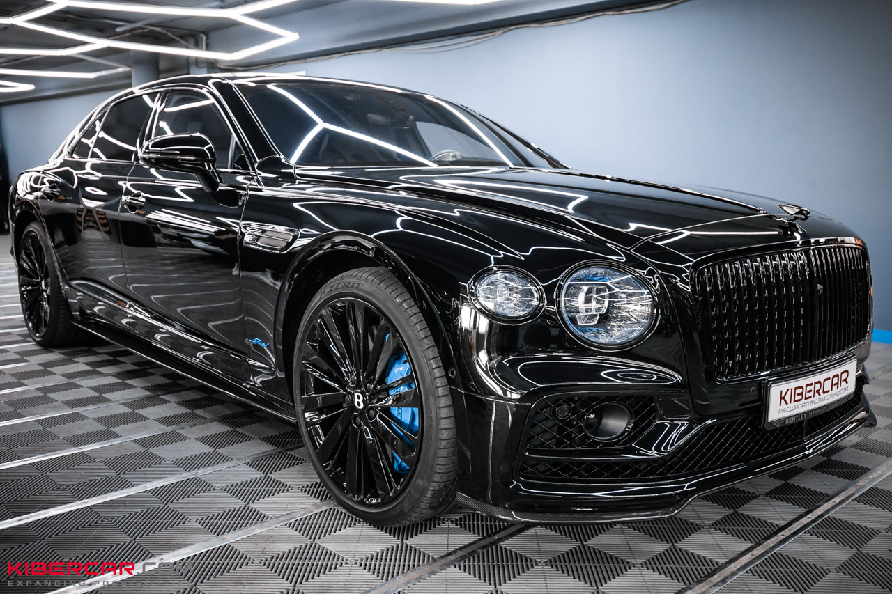 Bentley Flying Spur Speed 2025 спереди и сбоку: черные диски, голубой суппорт и шильдик Speed
