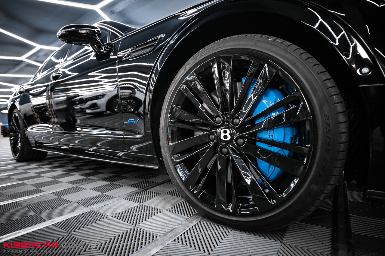 Переднее черное колесо Bentley с голубым суппортом, шильдик Speed на крыле, низкий ракурс